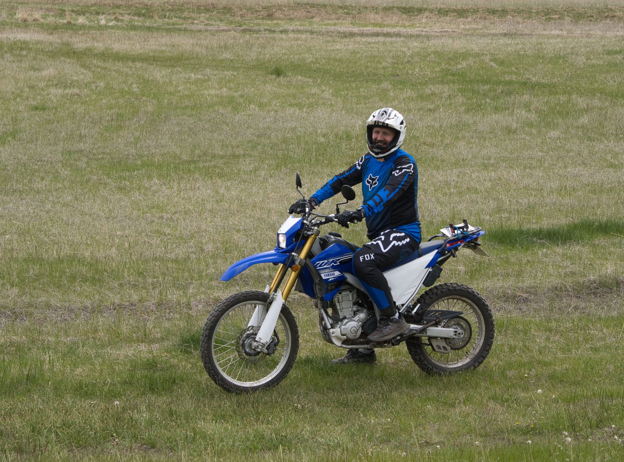 A rider on a blue Yamaha dual-sport bike stopped in an open grass meadow near Green Lake